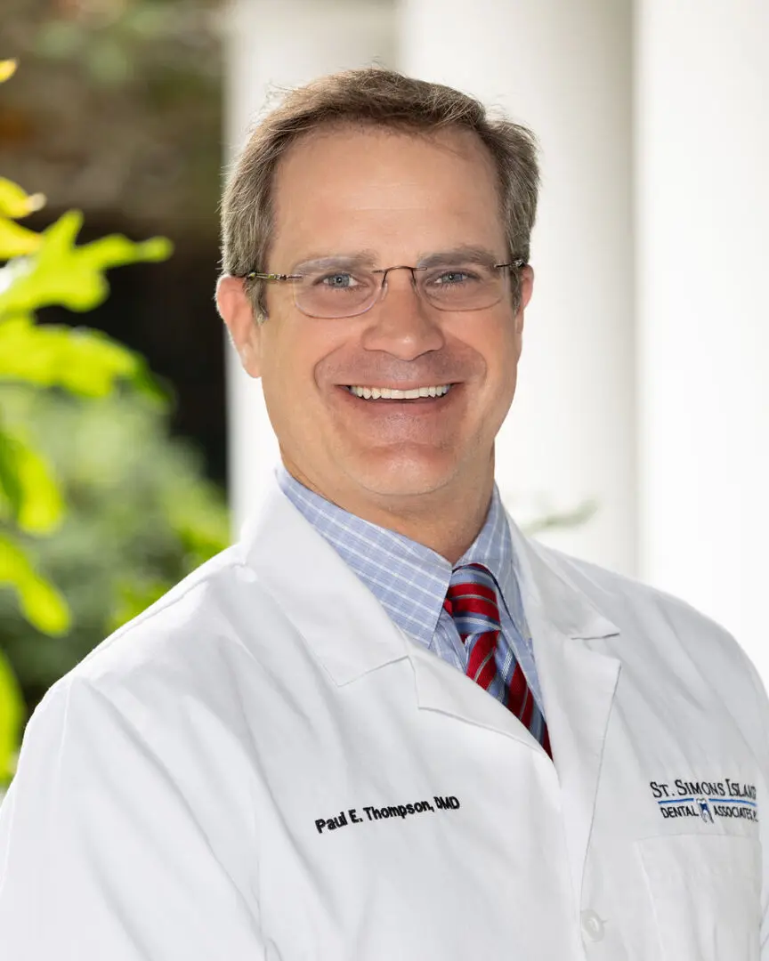 A man in white lab coat standing outside.