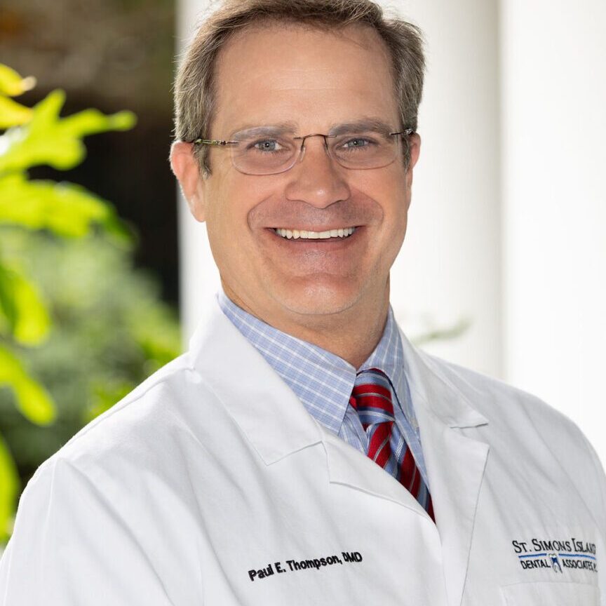 A man in white lab coat standing outside.